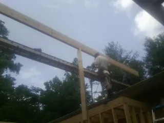 Carpenter setting a ridge beam over a new addition frame — Ice Dam Removal by Roofing Brothers in Jones