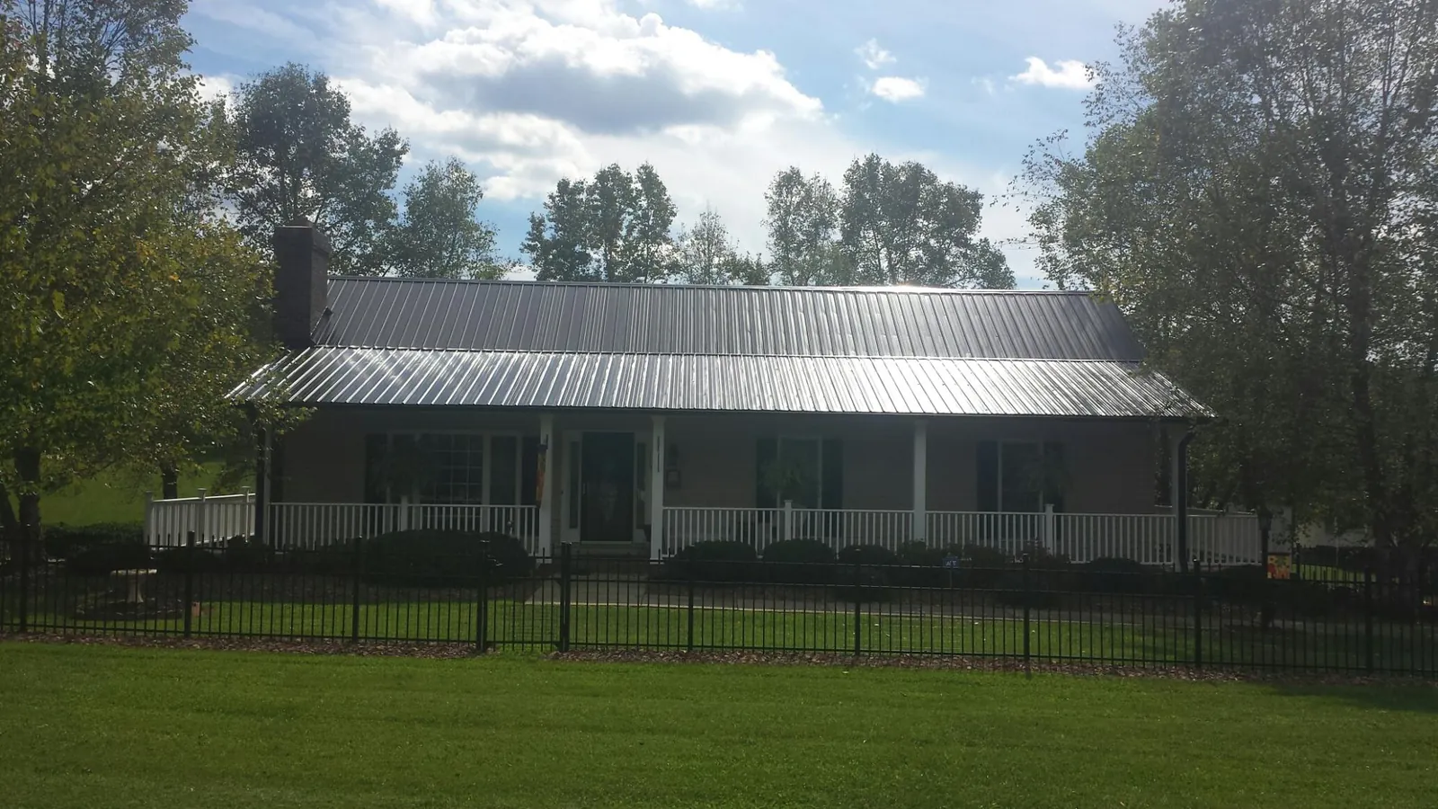Gray metal roof on a brick ranch with a full width front porch — Gutter Guard Installation work by our crew in Jones