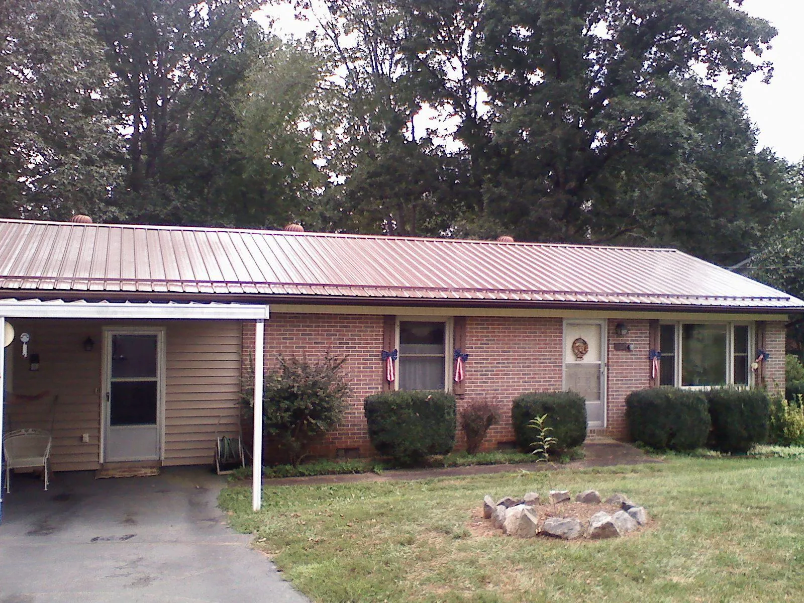 Bronze metal roof and carport on a brick ranch home — Roof Repair work by our crew in Jones